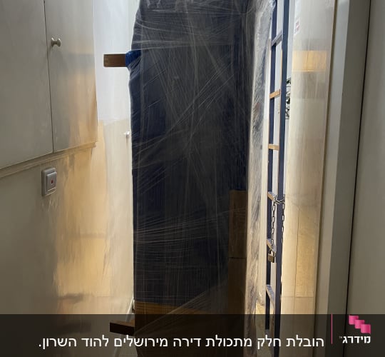 ארון עטוף בניילון על עגלה במסדרון צר